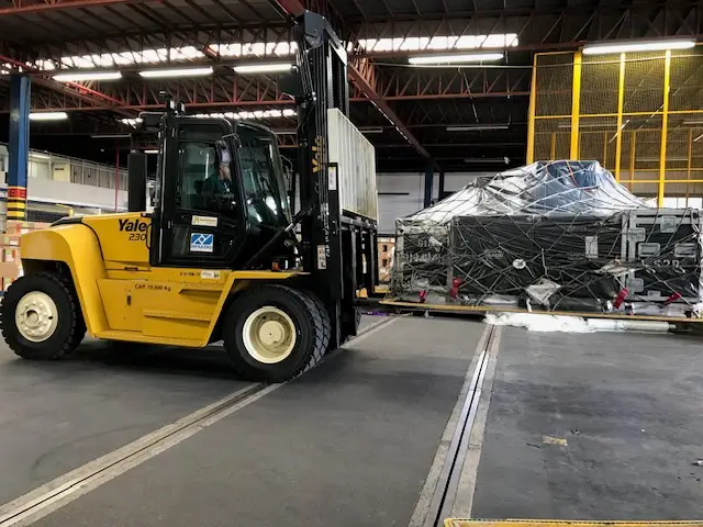 Forklift moving a secured high-value equipment pallet for an IMTS freight shipment