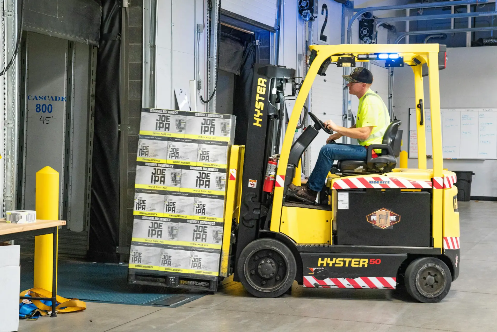 Warehouse worker using a Hyster forklift to load cases. Contact our freight shipping services team to learn more.